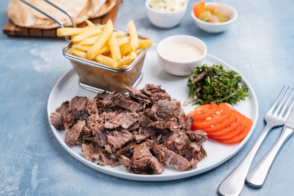 A mouth-watering Middle Eastern shawarma platter with fries and fresh vegetables.